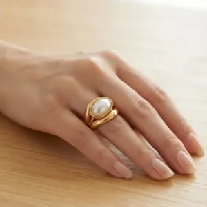 Bague dorée en acier inoxydable ornée d'une perle nacrée portée à la main