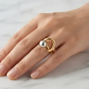Bague bicolore dorée avec perle sphérique argentée portée à la main
