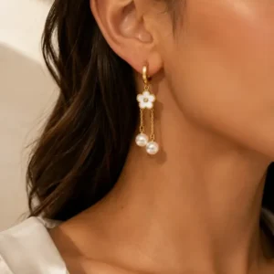 Boucles d'oreilles pendantes dorées fleur de nacre et perles portées à l'oreille
