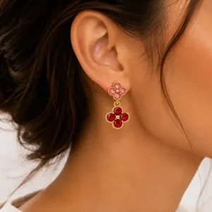 Boucles d'oreilles pendantes doubles trèfles dorées avec strass portées à l'oreille