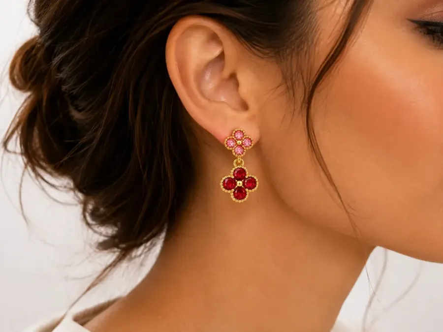 Boucles d'oreilles pendantes doubles trèfles dorées avec strass portées à l'oreille