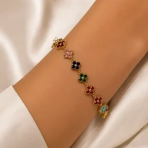 Bracelet chaîne trèfles multicolores doré porté au poignet d'une femme