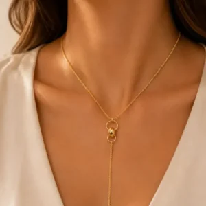 Collier cravate doré avec anneaux et chaîne pendante porté au décolleté