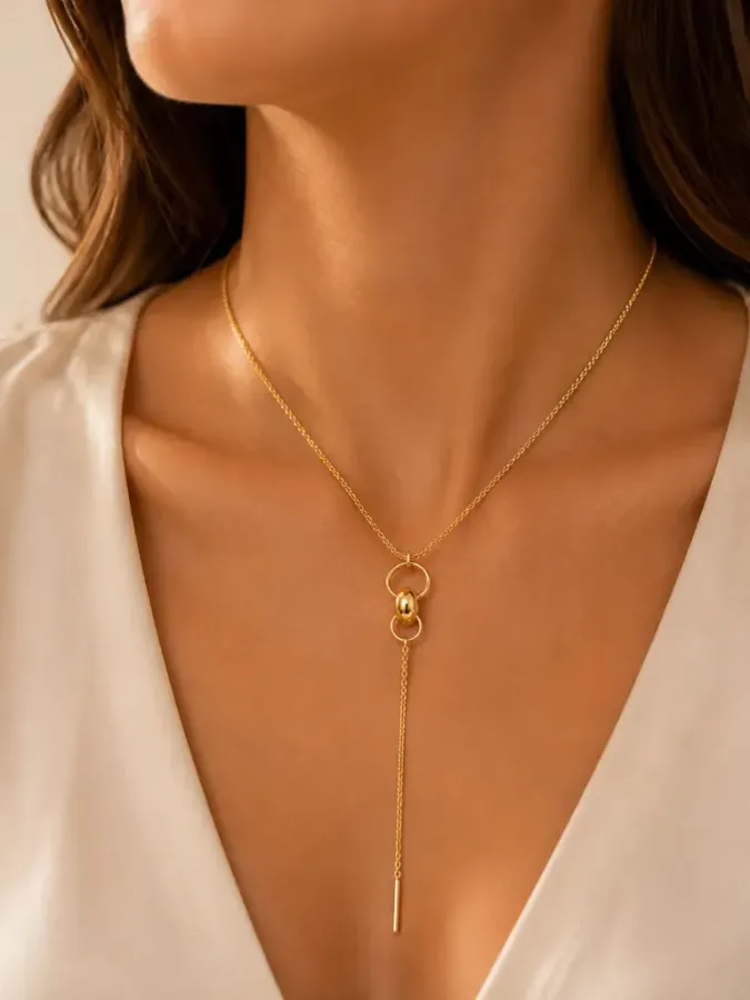Collier cravate doré avec anneaux et chaîne pendante porté au décolleté