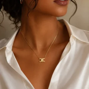 Collier chaîne fine pendentif double C doré porté par une femme