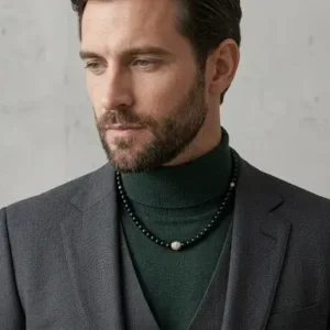Collier de perles noires porté par un homme sur un col roulé