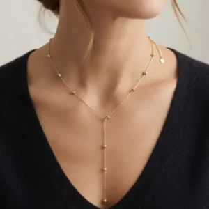 Collier sautoir fin style cravate doré porté délicatement au décolleté